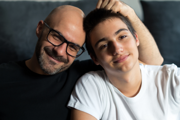 Bald man and teen boy sitting together