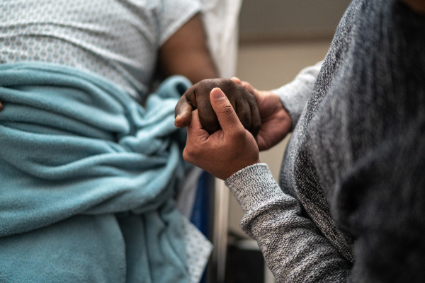 Close-up of two people holding hands in hospital