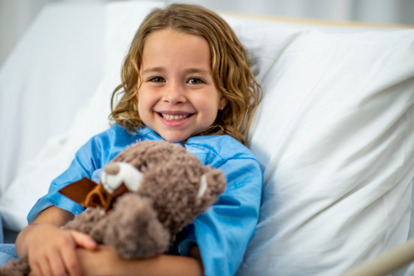 Young boy cuddling soft toy in a hospital bed