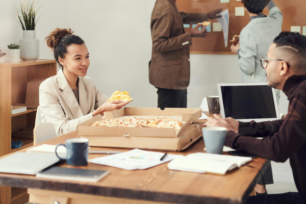 Group of people sharing pizza in an office environment