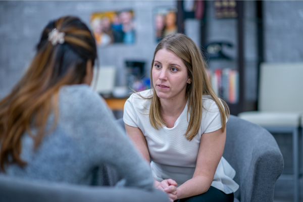 A two women sit talking with each other.