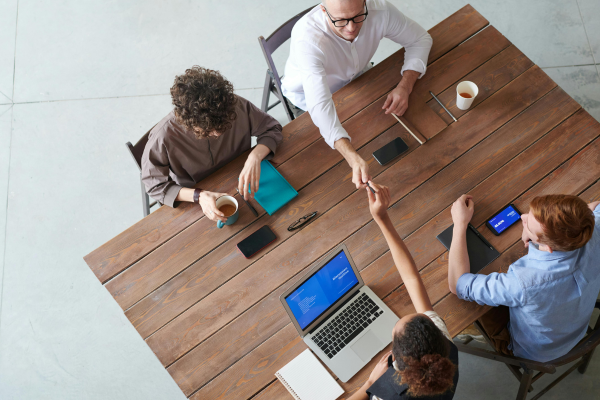 Aerial view of people sitting at meeting table with laptops