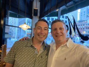 Two man at a restaurant posing for the camera