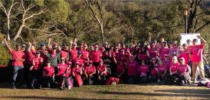 A large group of people in pink uniform gathered and smiling at the camera