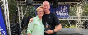 Two people together smiling holding winners trophy for the Kosi Challenge