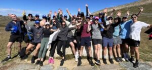 A group of people jumping in the air and cheering on the Mount Kosi track