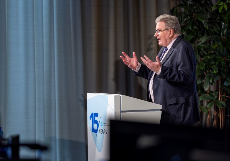 Man speaking at a podium to a conference